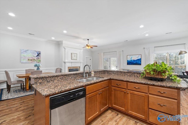 kitchen featuring a large fireplace, stainless steel dishwasher, stone countertops, ceiling fan, and sink