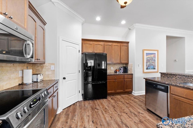 kitchen featuring stainless steel appliances, dark stone countertops, tasteful backsplash, hardwood / wood-style floors, and ornamental molding