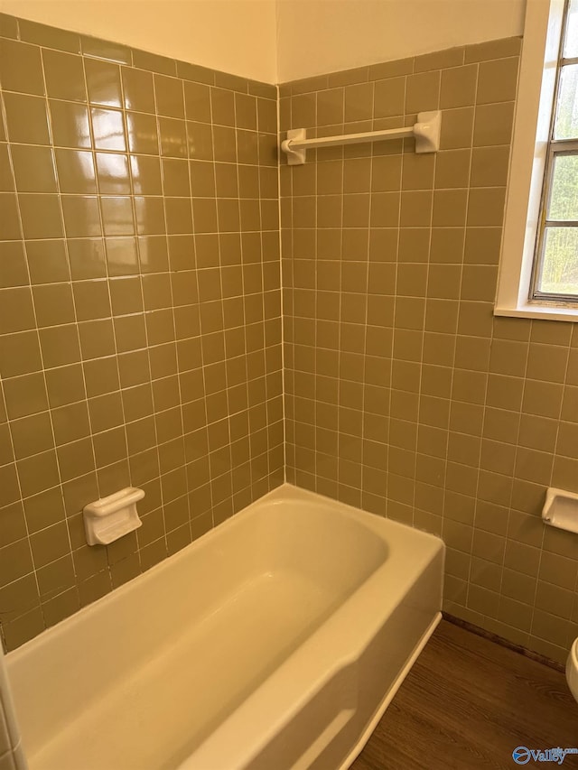 bathroom featuring wood-type flooring and tiled shower / bath