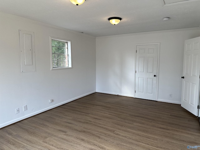 empty room featuring dark wood-type flooring, ornamental molding, and electric panel