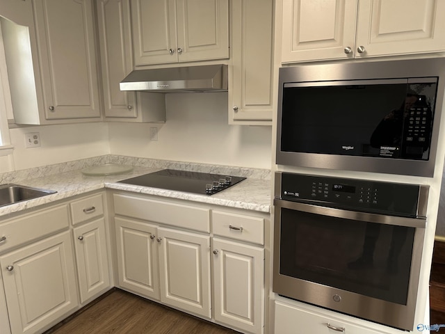 kitchen with sink, white cabinetry, appliances with stainless steel finishes, dark hardwood / wood-style floors, and exhaust hood