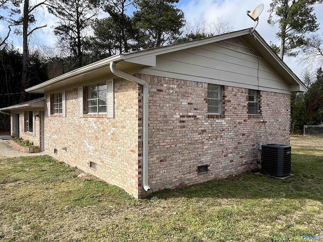 view of side of home featuring central AC unit and a yard