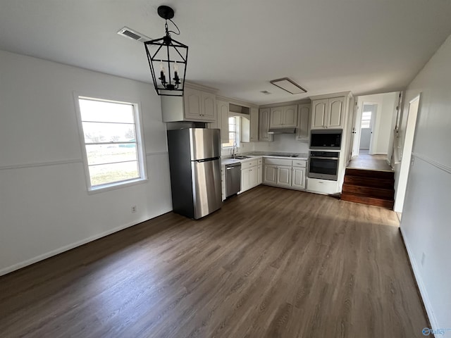 kitchen featuring sink, dark hardwood / wood-style flooring, hanging light fixtures, a notable chandelier, and stainless steel appliances