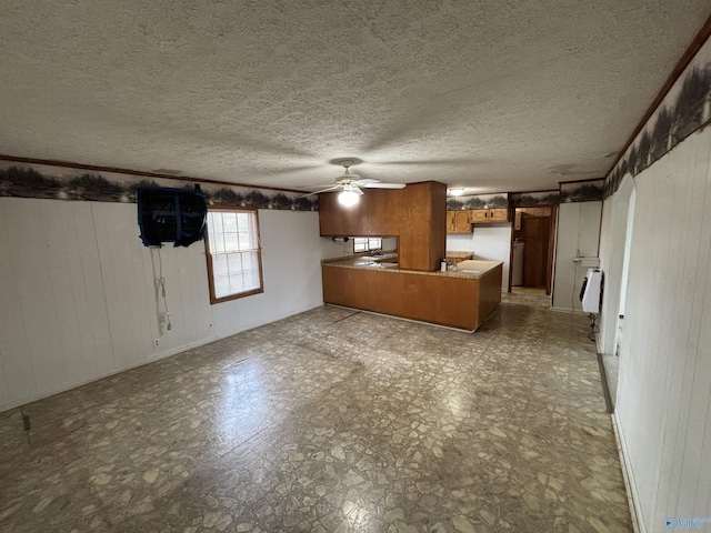 unfurnished living room with wooden walls, a textured ceiling, and ceiling fan