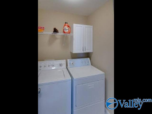 clothes washing area with cabinets and separate washer and dryer