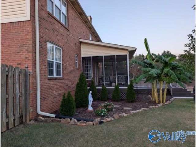 view of side of home with a sunroom and a yard