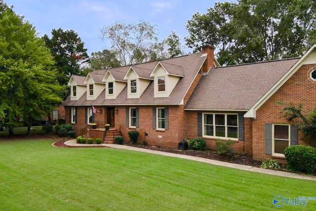 cape cod house with brick siding, a front yard, and a chimney