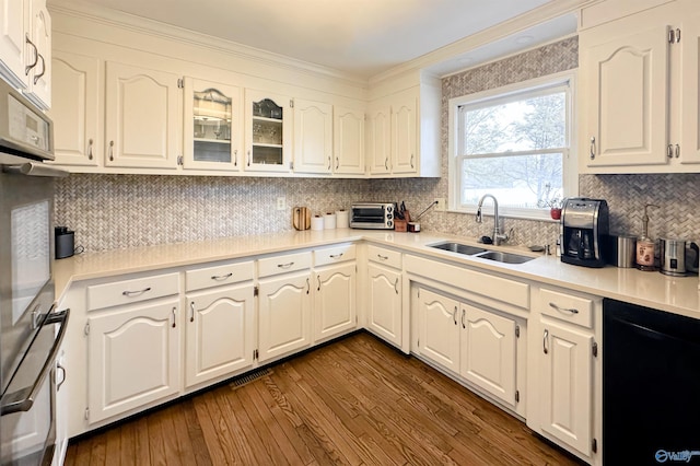 kitchen with dishwasher, a sink, light countertops, dark wood-style floors, and backsplash