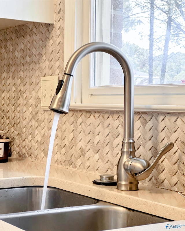 interior details with a sink, backsplash, and white cabinets