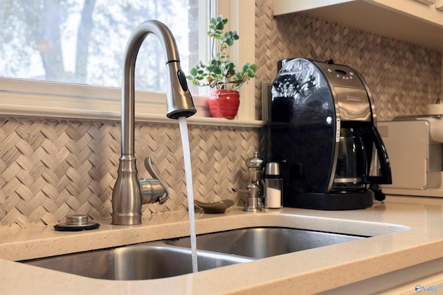 room details with light countertops, decorative backsplash, and a sink