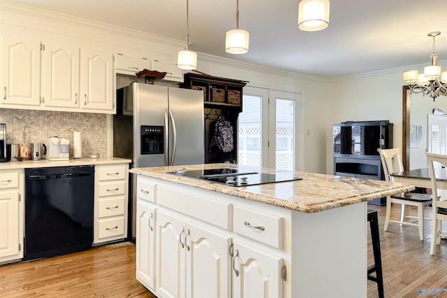 kitchen with a chandelier, light wood-style flooring, a center island, and black appliances