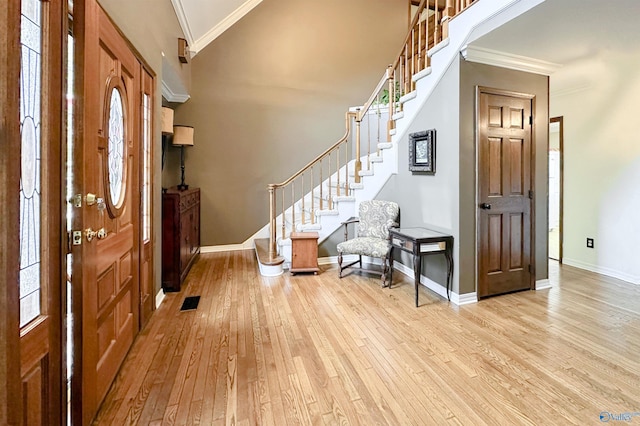 entryway with crown molding, baseboards, stairway, and light wood-style floors