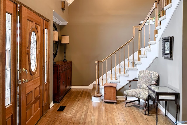 entrance foyer with visible vents, stairs, baseboards, plenty of natural light, and hardwood / wood-style flooring