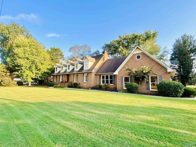 new england style home with a front yard, brick siding, and a chimney