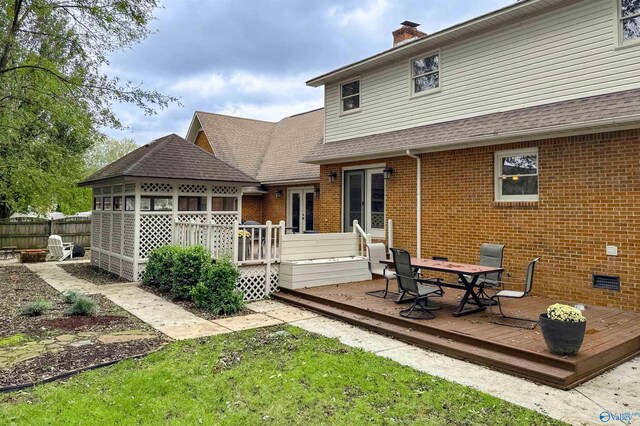 back of house featuring brick siding, a deck, french doors, and a chimney