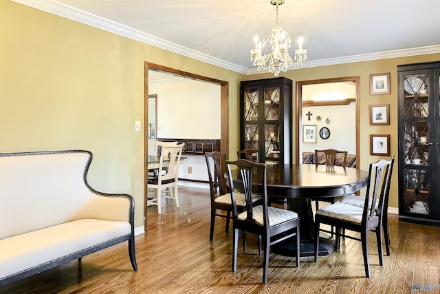 dining space featuring baseboards, an inviting chandelier, crown molding, and wood finished floors