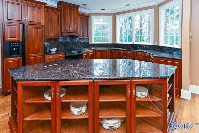 kitchen featuring black gas stove, light wood finished floors, ornamental molding, a sink, and open shelves