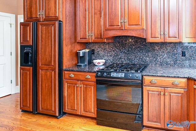 kitchen featuring light wood finished floors, black range with gas stovetop, paneled refrigerator, and brown cabinets