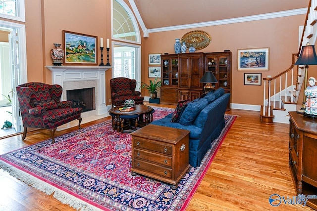 living room with a high end fireplace, ornamental molding, stairs, and wood finished floors