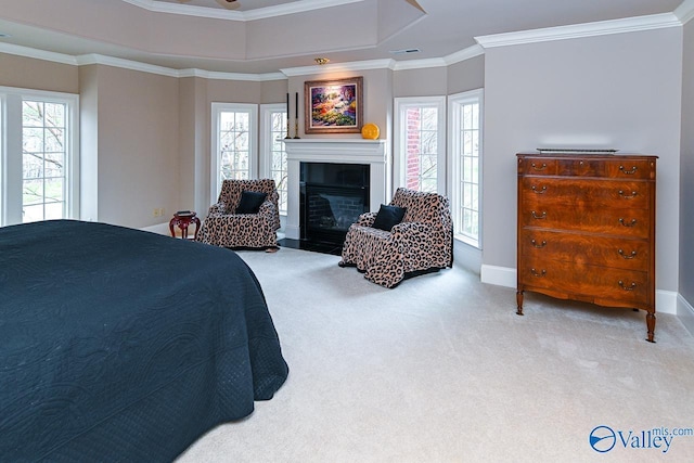 carpeted bedroom featuring crown molding, baseboards, a raised ceiling, visible vents, and a glass covered fireplace