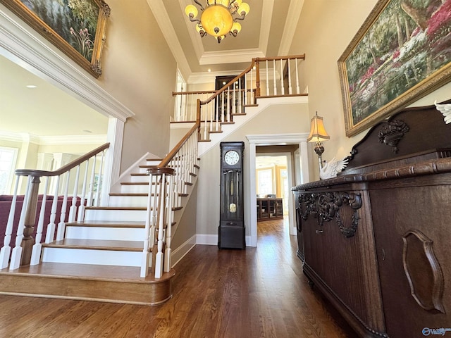 foyer with plenty of natural light, crown molding, wood finished floors, and stairway