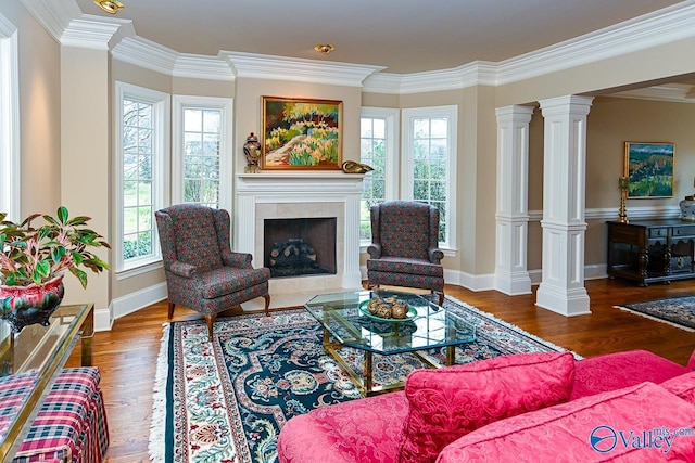 living area with decorative columns, crown molding, wood finished floors, a high end fireplace, and baseboards