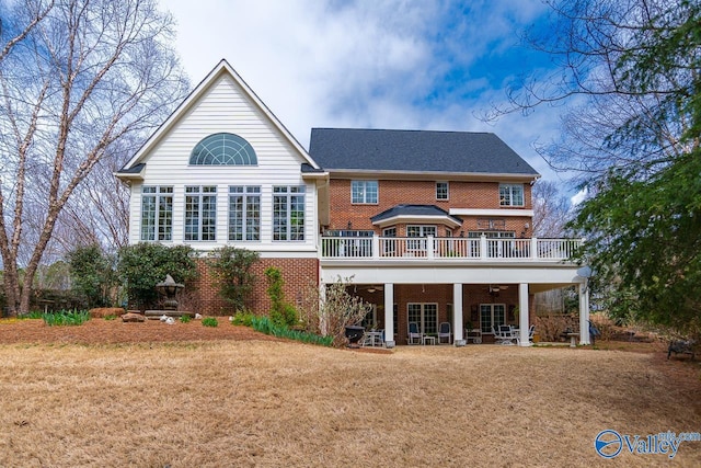 back of property with a yard, brick siding, and a deck