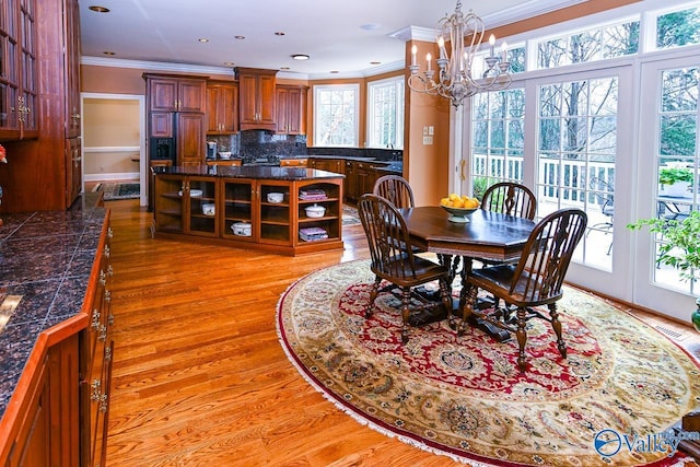 dining space featuring a notable chandelier, crown molding, light wood finished floors, and a wealth of natural light