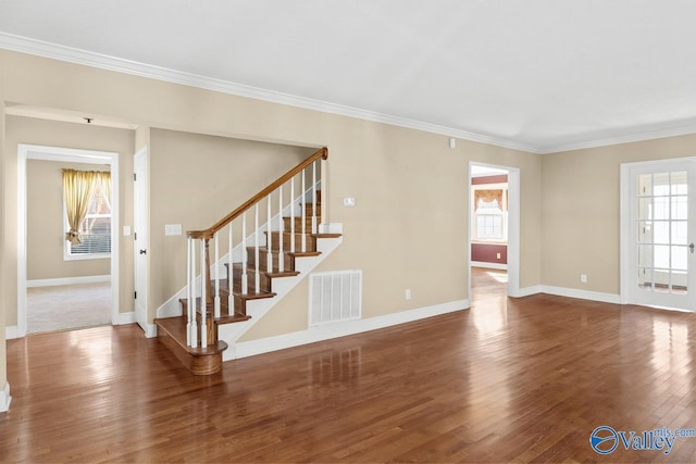 unfurnished living room with visible vents, wood finished floors, stairs, and ornamental molding