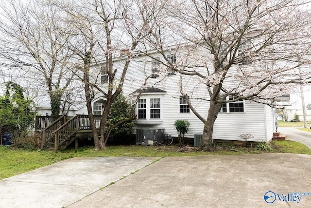 rear view of property featuring a wooden deck, central AC unit, and stairway