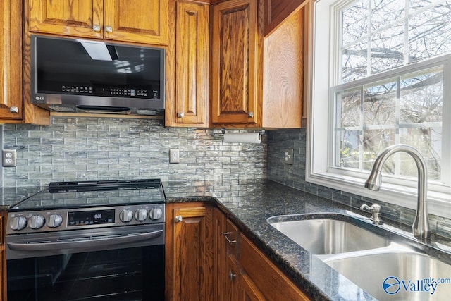 kitchen with a sink, brown cabinetry, backsplash, and stainless steel appliances