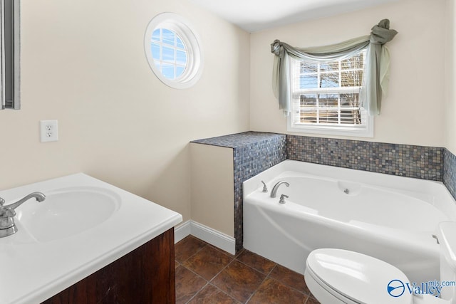 bathroom featuring toilet, a bath, vanity, and baseboards