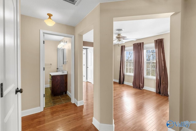 hall featuring hardwood / wood-style flooring, baseboards, and visible vents