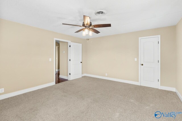 empty room featuring visible vents, carpet flooring, a ceiling fan, and baseboards