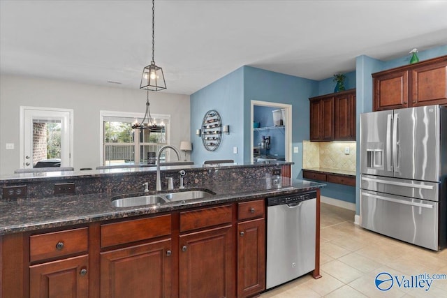 kitchen featuring sink, appliances with stainless steel finishes, dark stone countertops, tasteful backsplash, and decorative light fixtures