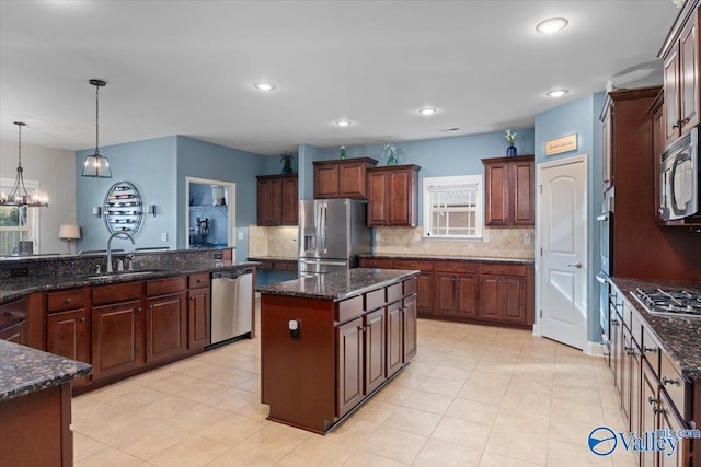 kitchen featuring appliances with stainless steel finishes, decorative light fixtures, tasteful backsplash, sink, and a center island