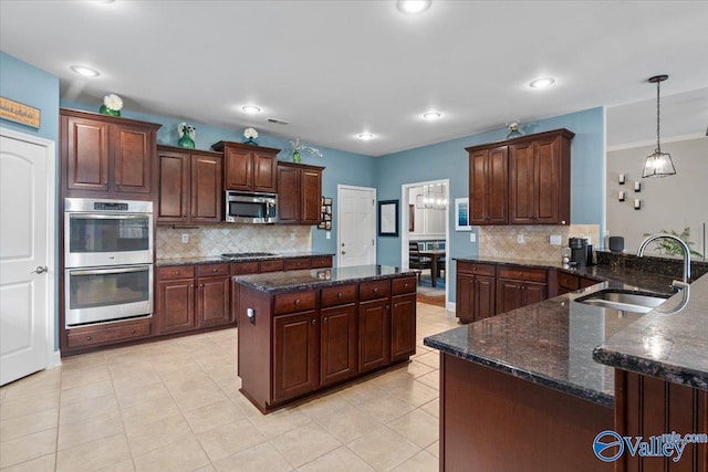 kitchen with dark brown cabinetry, sink, decorative light fixtures, appliances with stainless steel finishes, and kitchen peninsula