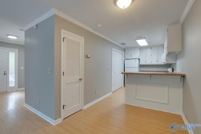 kitchen with kitchen peninsula, white cabinetry, light wood-type flooring, ornamental molding, and white refrigerator