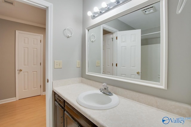 bathroom with wood finished floors, visible vents, vanity, and ornamental molding