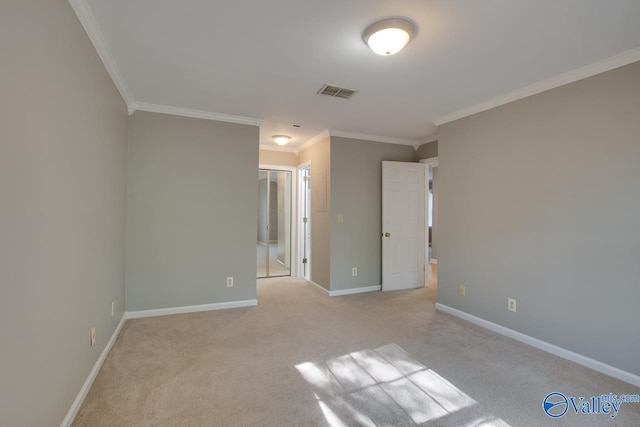 unfurnished room featuring baseboards, visible vents, light colored carpet, and crown molding