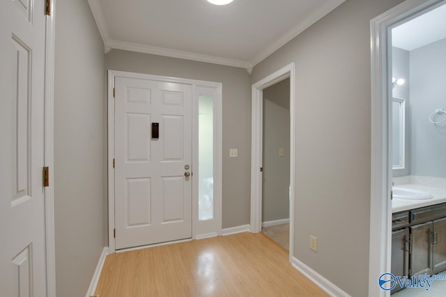 foyer with light hardwood / wood-style floors, ornamental molding, and sink