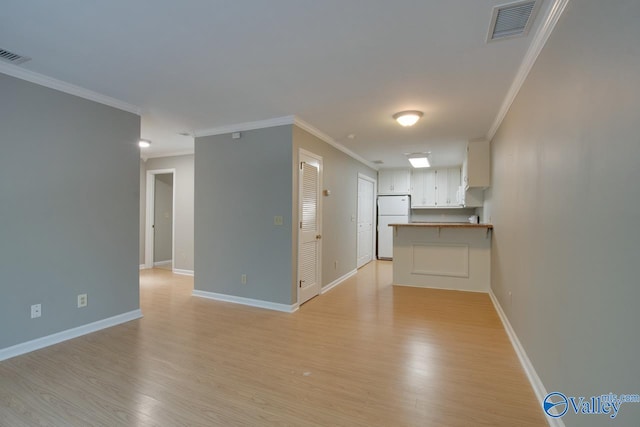 empty room with crown molding and light wood-type flooring