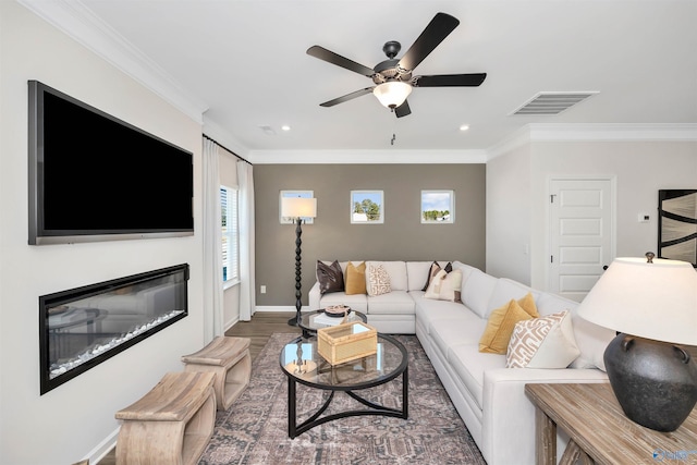 living room featuring a healthy amount of sunlight, dark wood-type flooring, ceiling fan, and ornamental molding