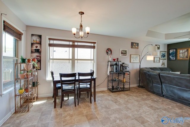 dining space with stone finish flooring, an inviting chandelier, and baseboards