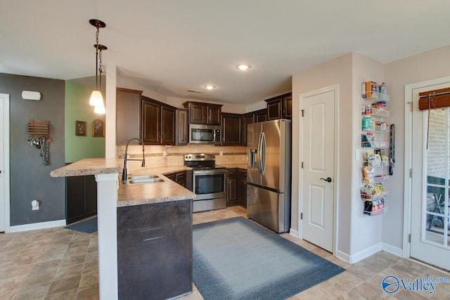 kitchen featuring a peninsula, a sink, dark brown cabinetry, light countertops, and appliances with stainless steel finishes