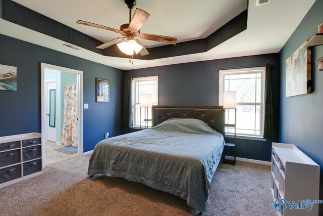 bedroom with a ceiling fan, carpet, a raised ceiling, baseboards, and visible vents