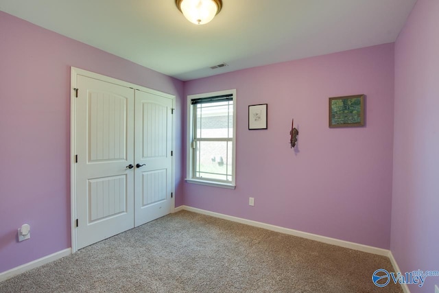 unfurnished bedroom with baseboards, visible vents, carpet, and a closet