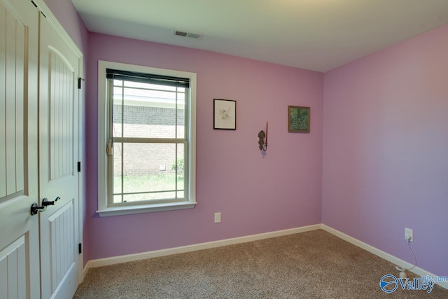 empty room with carpet floors, visible vents, and baseboards