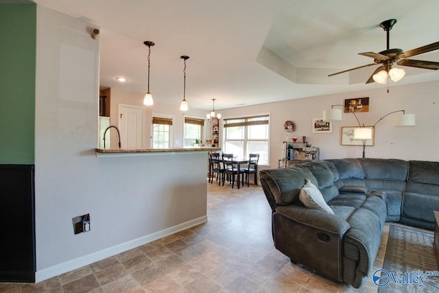 living area with ceiling fan with notable chandelier and baseboards