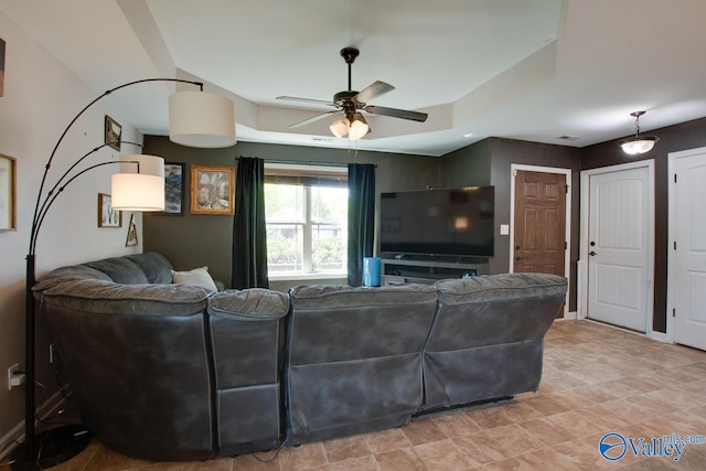 living room with a raised ceiling and ceiling fan